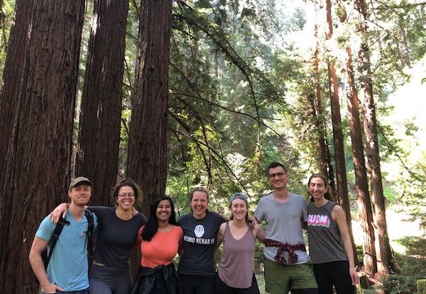 Students and staff embracing on a hike in front of trees