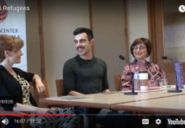 Screenshot of a center video where three people sit at a desk and smile at each other.