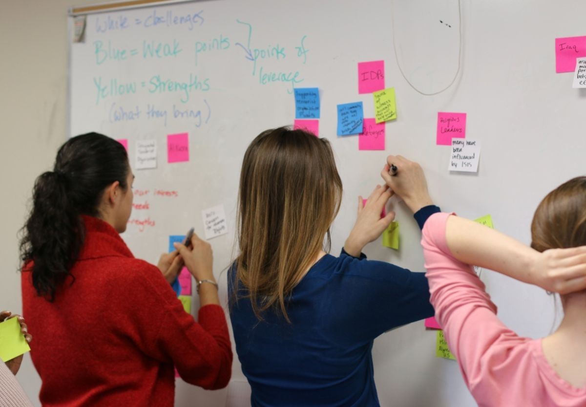 Students work together and write on a white board.