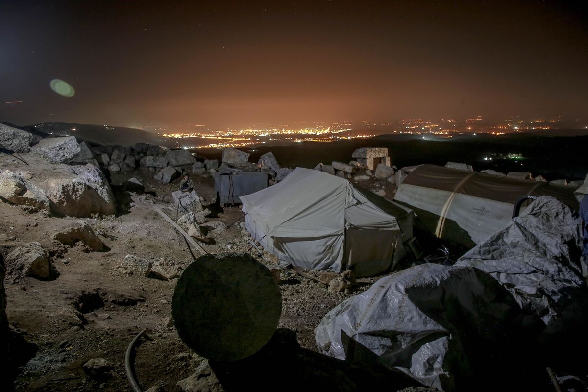 Refugee tent at night overlooking city.